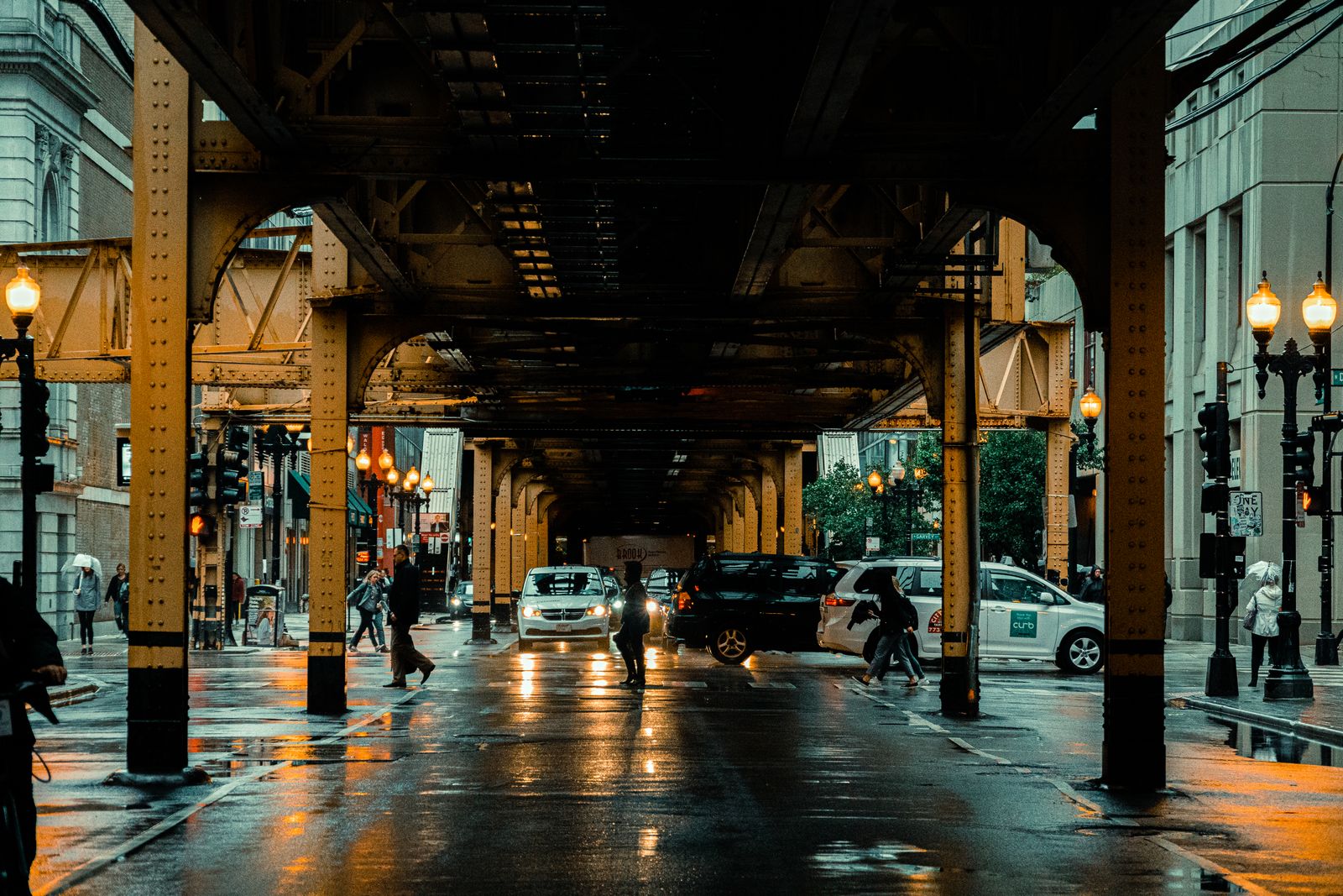 A Chicago street beneath elevated "L" train tracks on a rainy day